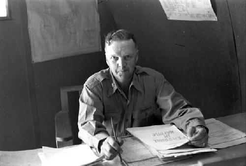 Military Man (Johnson name tag) sitting at desk with papers.