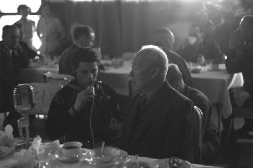 Sailor speaking to man as microphone sits on the table.