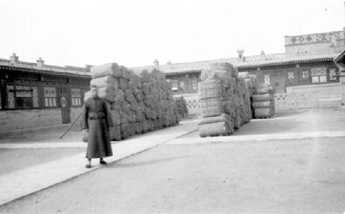 Man with stacks of bundled packs outside building