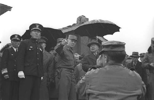 Military man and man standing under umbrella.