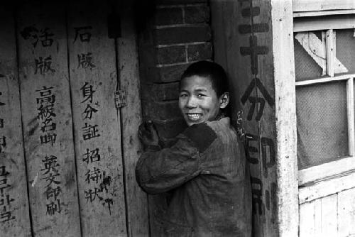 Man opening wooden door painted with Chinese words.