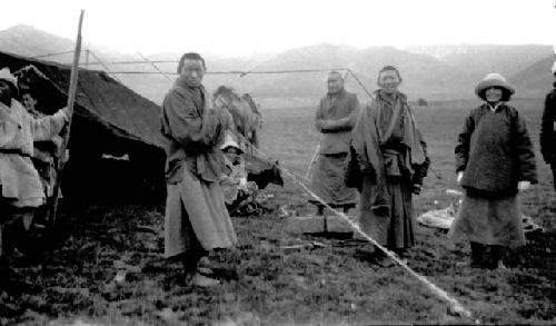 People standing outside of tent near mountains