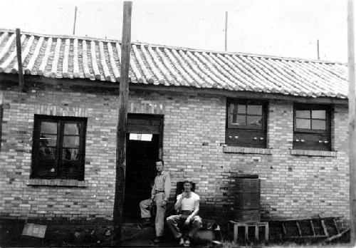 Men posing in front of house