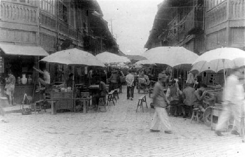 People at a street market with umbrellas over stands