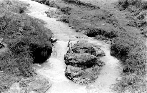 Man on a rock in the middle of a river