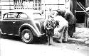 Boy posing while men work on car