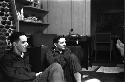 Two military men sitting on floor.