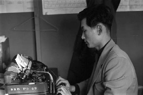 Man typing on manual typewriter.