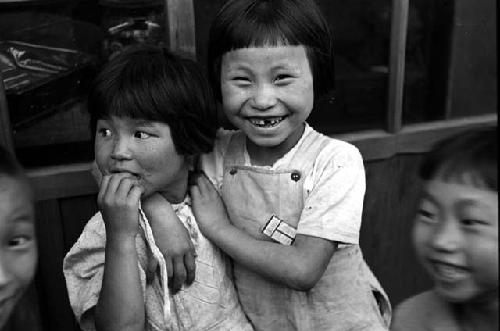 Two girls standing; children beside them.