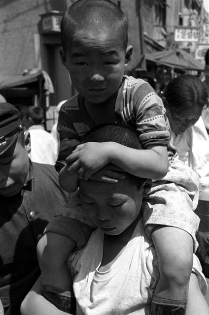 Young boy sitting on back of woman, grabbing her head