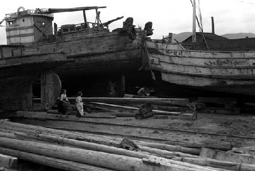 Two women walking along docks, large boats around them.