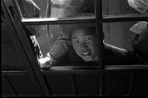 Boy looking in through window; other kids beside him.