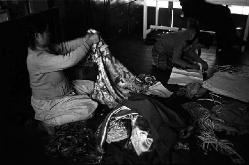 Women sitting on floor, handling fabrics.