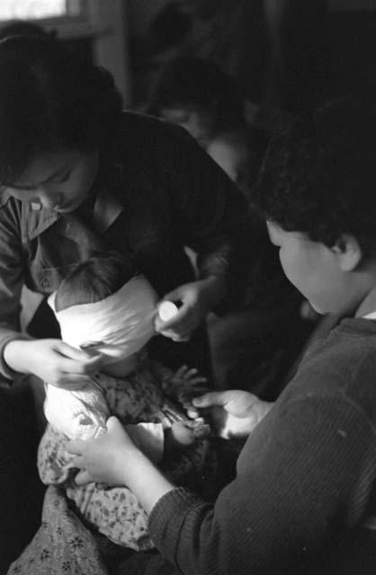 Woman looking as child's head is bandaged