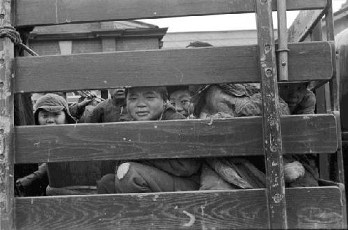 Men seen through the bed slats of a pick-up truck.