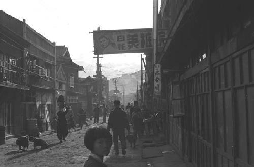 Street scene in town with dogs and girl in foreground.