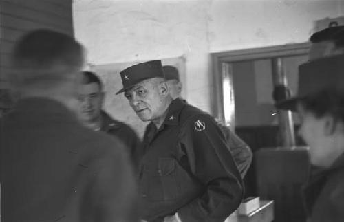 General William S. Whitcomb talking with soldiers indoors.