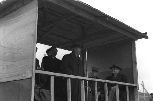 Men in two-sided shed with microphone stand.