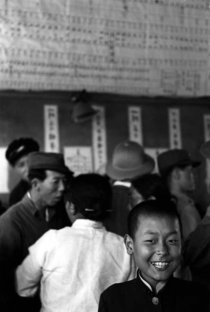 Boy smiling; crowd of people behind him.