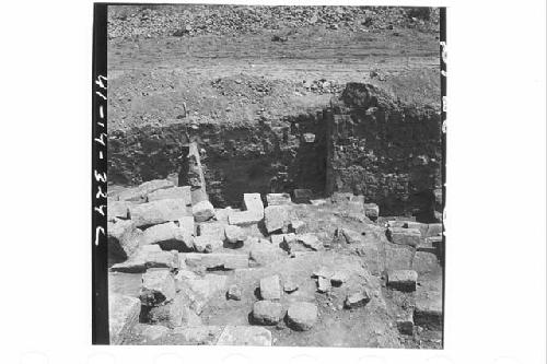 Oblique downward panorama of fallen, squared wall stones of N. exterior wall.  F