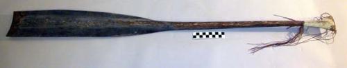 Paddle of dark endogenous wood, having upper part of handle woven of +