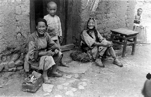 Women and boy sitting near the doorway of a house