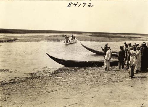 Life scene river with small boats and men Marsh Arab Iraq