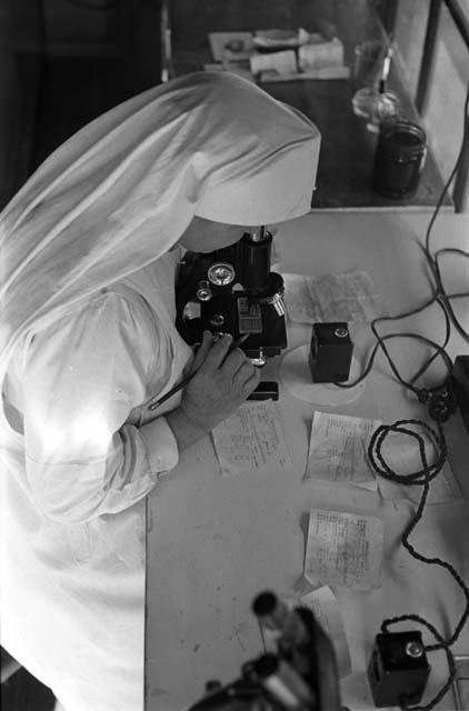 Nun looking into microscope.