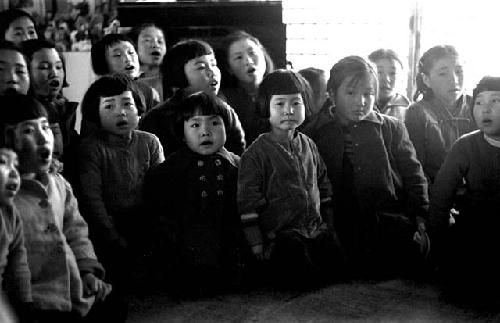 Group of seventeen young children singing (inside)