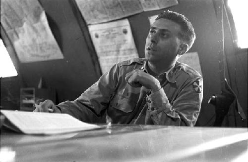 Military man (Cohen name tag) sitting at desk with book.