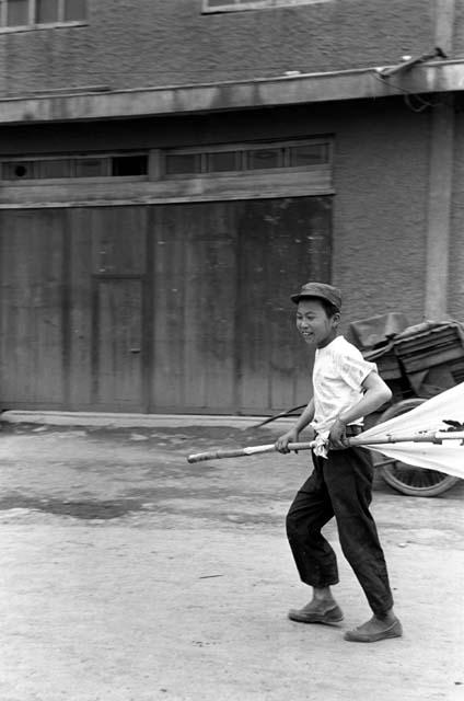 Boy on the street pulling at bamboo pole.