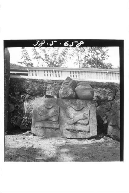 Two cross-legged and cross-armed figures on the same stone in relief