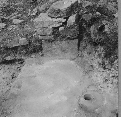 Neck of pottery vessel set in floor of a room.