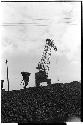 Cranelike construction machine lifting an object and a worker walking