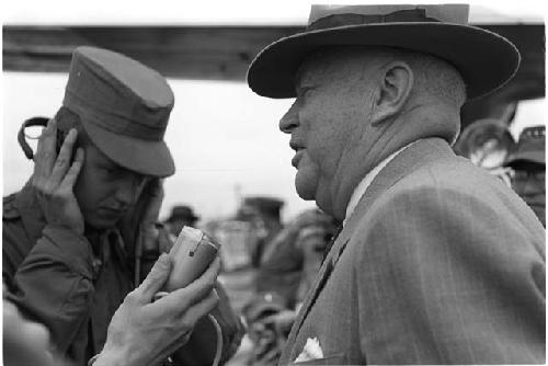 Microphone being held up to a man wearing a suit and hat