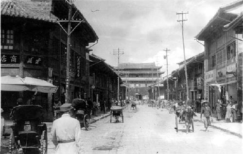 People and carts on street with buildings on both sides