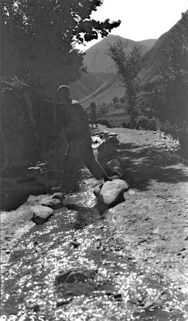 Man crossing stream in mountains