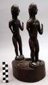 2 tall wooden figures on 1 base - possibly used for condiments