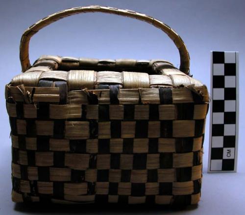 Basket, square, woven fiber, brown and buff strips, bale handle, broken areas