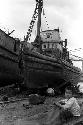 Boy sitting in front of large docked ship.