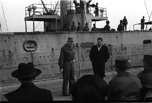 Crowd in front of ship two men facing