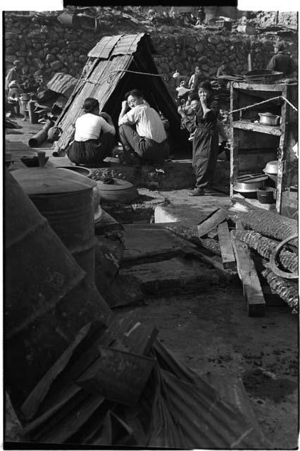 men working on a roof or hut, child looking at photographer