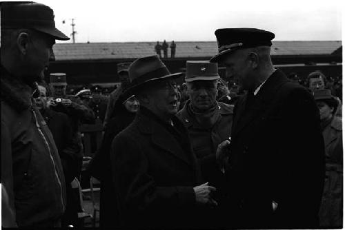 Man in hat talking to man in uniform in a crowd