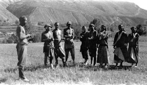 People standing in field near mountains