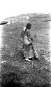 Tibetan man holding stick, building in background