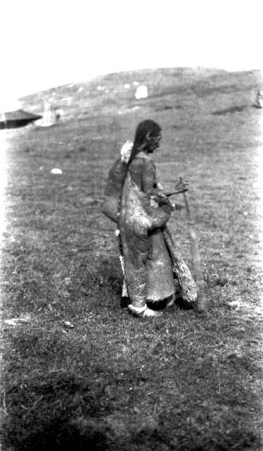 Tibetan man holding stick, building in background