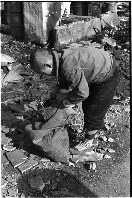 Boy bending down towards a sack