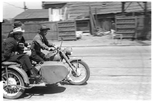 three men riding a three seater motorcycle