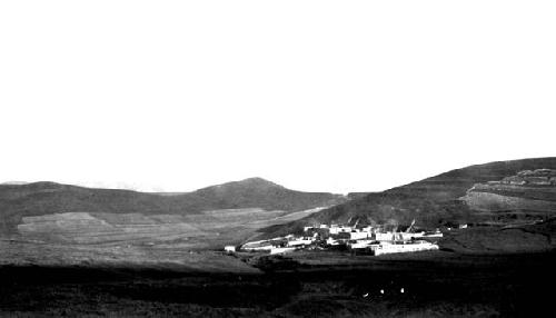 Buildings among hills fields in distance