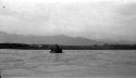 People rowing raft on river, mountains in background